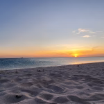 Sunset over a wide white-sand beach on Aruba's west coast